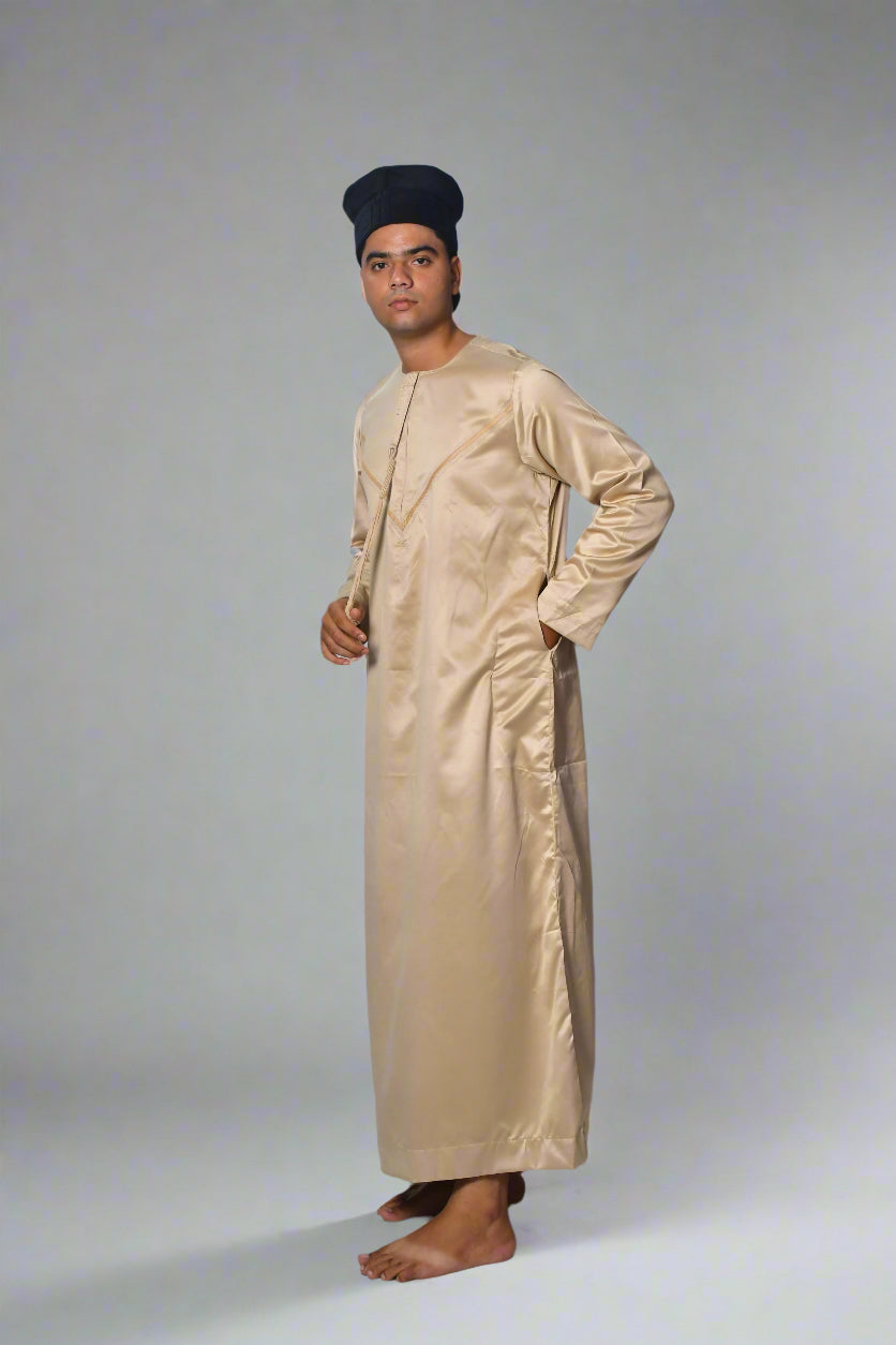 Man wearing a beige traditional outfit and black cap on a white background