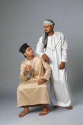 Two men in traditional attire sitting on a bench in a store.