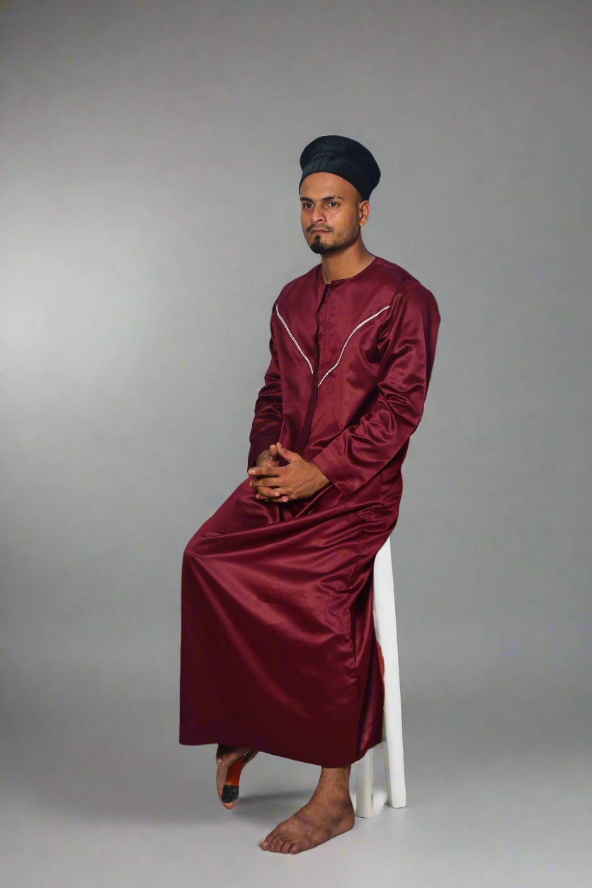 Two individuals wearing maroon and black outfits standing on a white background.